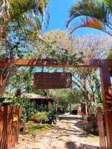 a wooden archway with a sign in a yard at Pousada Raízes da Guarda in Guarda do Embaú