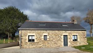 ein kleines Backsteinhaus mit schwarzem Dach in der Unterkunft Maison paisible in Pleucadeuc