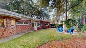 a brick house with blue chairs in the yard at Meet Me At Sunset in Jekyll Island