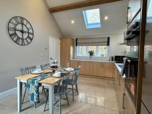 a kitchen with a table and a clock on the wall at The Lodge - Elegant Peaceful Countryside Escape in Bishops Cannings