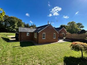 a small brick house in a yard at The Lodge - Elegant Peaceful Countryside Escape in Bishops Cannings