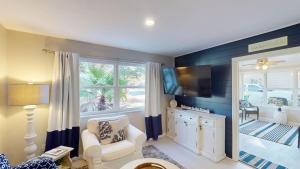 a living room with a white chair and a television at Sea Haven Duplex A in Jekyll Island