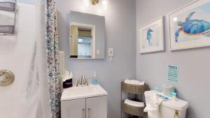 a bathroom with a sink and a toilet and a mirror at Sea Haven Duplex A in Jekyll Island +12 photos