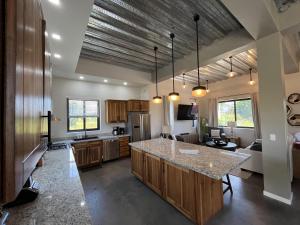 a kitchen with a large island in a room at Emerald Blue Villa - Modern 2BR Villa with Rooftop Lounge Pool in Placencia Village