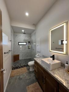 a bathroom with a sink and a toilet and a shower at Emerald Blue Villa - Modern 2BR Villa with Rooftop Lounge Pool in Placencia Village +11 photos