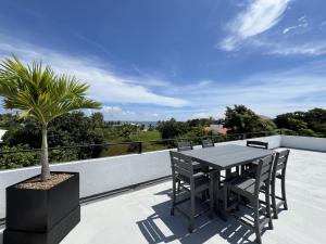 a table and chairs on a balcony with a palm tree at Emerald Blue Villa - Modern 2BR Villa with Rooftop Lounge Pool in Placencia Village