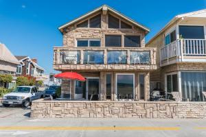 Centrally Located 3Br Oceanfront W Great Value & Views By Beachview Rentals في شاطئ نيوبورت: منزل أمامه مظلة حمراء