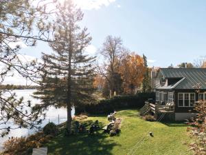 a house with people sitting on the lawn next to the water at Le Selby in Dunham