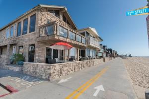 7Br Beachfront Retreatstunning Ocean Views & Walkable Fun By Beachview Rentals في شاطئ نيوبورت: مبنى على الشاطئ مع مظلة