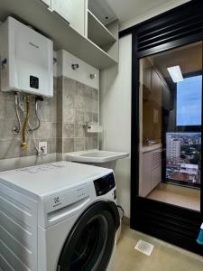 a white washing machine in a bathroom with a window at 2-bedroom apartment, Home Office and panoramic view in São Carlos