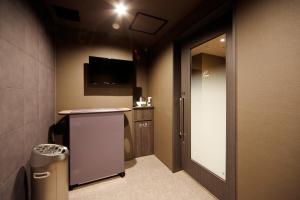 a room with a hallway with a door and a television at Dormy Inn Nagano in Nagano