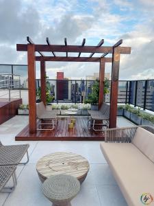 a rooftop deck with a wooden pergola and chairs at Compact Time 1402 in Tambaú +29 photos