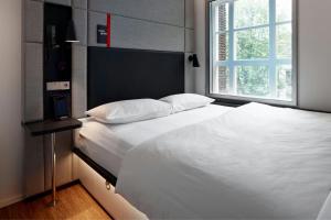 Un dormitorio con una gran cama blanca con ventana. en citizenM Amstel Amsterdam, en Ámsterdam