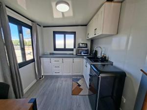 a small kitchen with white cabinets and a black refrigerator at Mackenzie Motels in Fairlie