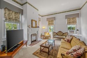 a living room with a tv and a fireplace at The Manor - Historic Mansion, Wifi, Covered Porch, Screen Porch, King Bed, Walk to Spas, Shops & Restaurants in Berkeley Springs