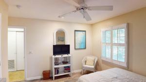 a bedroom with a ceiling fan and a tv at Beachbreak in Jekyll Island
