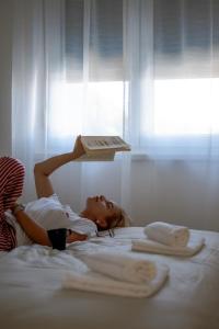 Eine Frau lag mit einem Buch auf dem Kopf auf einem Bett. in der Unterkunft LALA & DAUGHTERS Apartment in Vrnjačka Banja