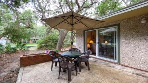 a patio with a table and chairs and an umbrella at Very Nice Cottage in Jekyll Island