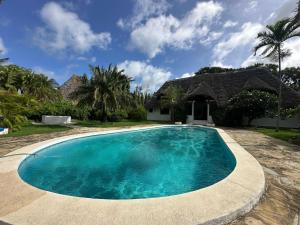 a swimming pool in front of a house at Villa Elizabeth by the Golf Club in Malindi