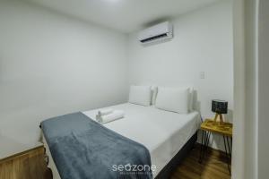 um quarto com uma cama branca e uma pequena mesa em Sua estadia completa com piscina e academia em Poços de Caldas - NGO em Poços de Caldas mais 29 fotografias