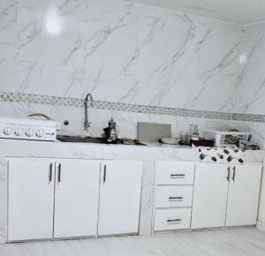 une cuisine blanche avec des armoires blanches et un mur en marbre dans l'établissement DEPARTAMENTO EN Riobamba ALBORADA VIP, à Riobamba