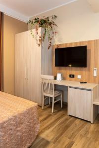 - une chambre avec un bureau, une télévision et un lit dans l'établissement Lepanto Central, à Messina