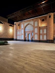 un grand bâtiment en briques avec un grand plancher en bois dans l'établissement Movarounnahr - Гостевой дом, à Margilan