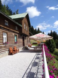 uma casa com um pátio e um guarda-chuva e flores em Penzion Táňa em Pec pod Sněžkou