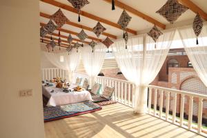 Cette chambre dispose d'un lit et de rideaux sur un balcon. dans l'établissement Movarounnahr - Гостевой дом, à Margilan