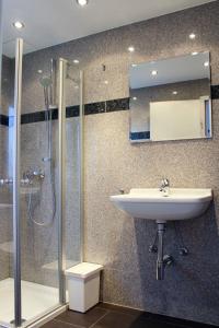 a bathroom with a sink and a shower with a mirror at Pension Nordsee in Norddeich