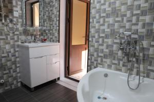 une salle de bain avec une baignoire, un lavabo et un miroir dans l'établissement Movarounnahr - Гостевой дом, à Margilan 23 autres photos