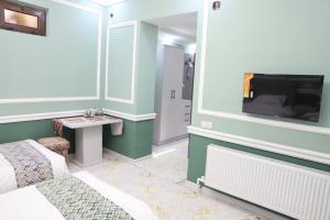 Cette chambre comprend un lit, une télévision et une table. dans l'établissement Movarounnahr - Гостевой дом, à Margilan