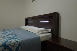 a bed with a wooden headboard next to a table at Hotel Mina in Craiova