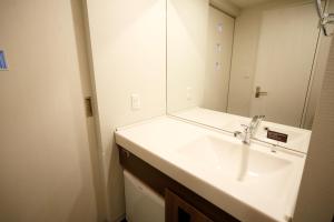 a bathroom with a white sink and a mirror at Dormy Inn Nagano in Nagano