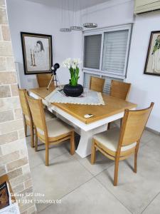 ein Esstisch mit Stühlen und einer Vase mit Blumen in der Unterkunft דירה לאירוח בכרמיאל מלון in Karmi’el