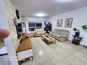 ein Wohnzimmer mit zwei Sofas und einem Fernseher in der Unterkunft דירה לאירוח בכרמיאל מלון in Karmi’el