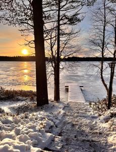 Ein Steg im Schnee neben einem See im Sonnenuntergang in der Unterkunft Kalliorinne - Lakefront Villa in Ruka