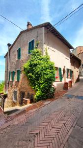 an old brick building with green shutters on a street at Ciliano 16 in Montepulciano