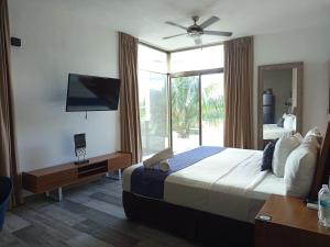 ein Hotelzimmer mit einem Bett und einem Fernseher in der Unterkunft Hotel Piedra del Caribe Puerto Morelos in Puerto Morelos