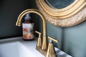een wastafel in de badkamer met een gouden kraan en een fles zeep bij The Lincoln House Inn in Bowling Green +64 foto's