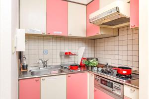 uma cozinha com armários cor-de-rosa e brancos e um lavatório em Duetoir 801 / Vacation STAY 7558 em Nagoya