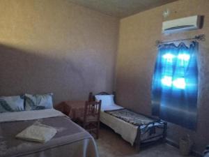 ein Schlafzimmer mit zwei Betten, einem Stuhl und einem Fenster in der Unterkunft Gite Omar merzouga in Merzouga