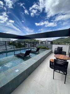 a patio with chairs and a pool on a building at Loft com Piscina no Rooftop centro de Blumenau in Blumenau
