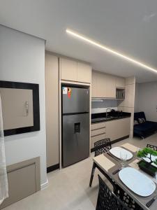 a kitchen and living room with a table and a refrigerator at Loft com Piscina no Rooftop centro de Blumenau in Blumenau