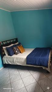 a bed in a room with a blue wall at Chácara maravilha in Monte Sião