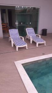 two blue and white chairs next to a swimming pool at casa a 600 metros da praia in Peruíbe
