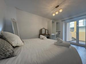 een slaapkamer met een wit bed met handdoeken erop bij Charming Seaside Flat in Paul do Mar