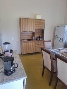a kitchen with a counter and a table and a refrigerator at Sítio com casa Rústica Itamonte in Santana do Capivari