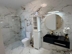 een badkamer met een toilet, een wastafel en een spiegel bij Charming Seaside Flat in Paul do Mar