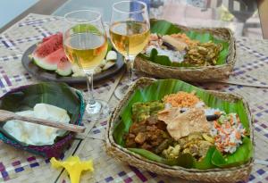 a table with three dishes of food and two glasses of wine at EcoBlueprint Garden in Pannala